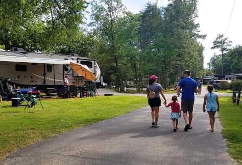 family walking on road away from camera between RV parking spots